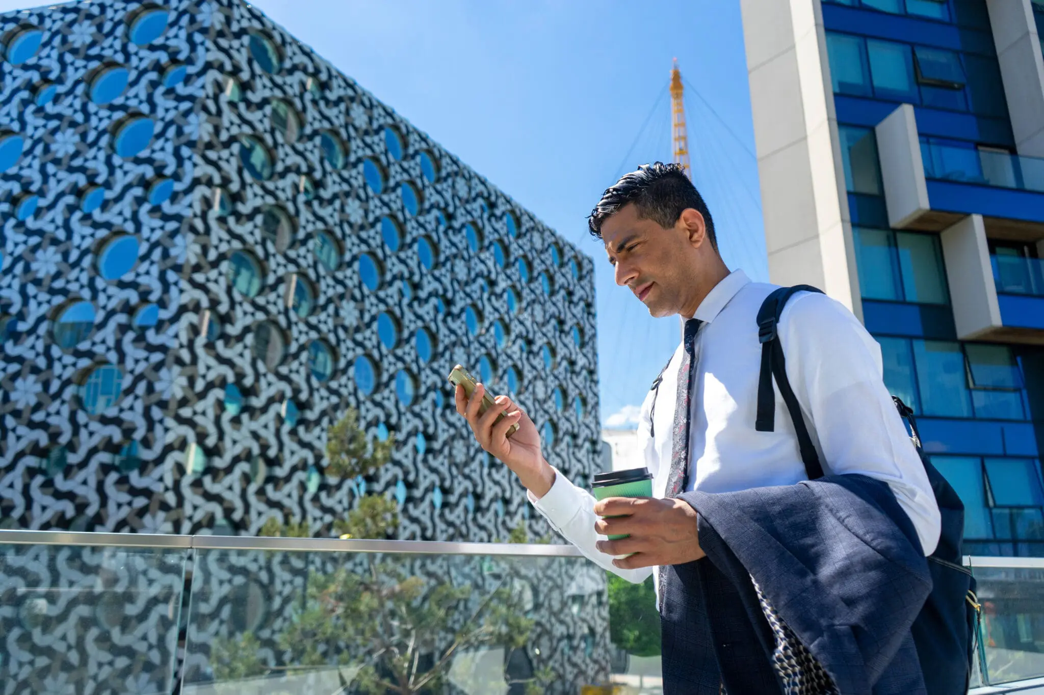 Businessman walking in business district and using phone